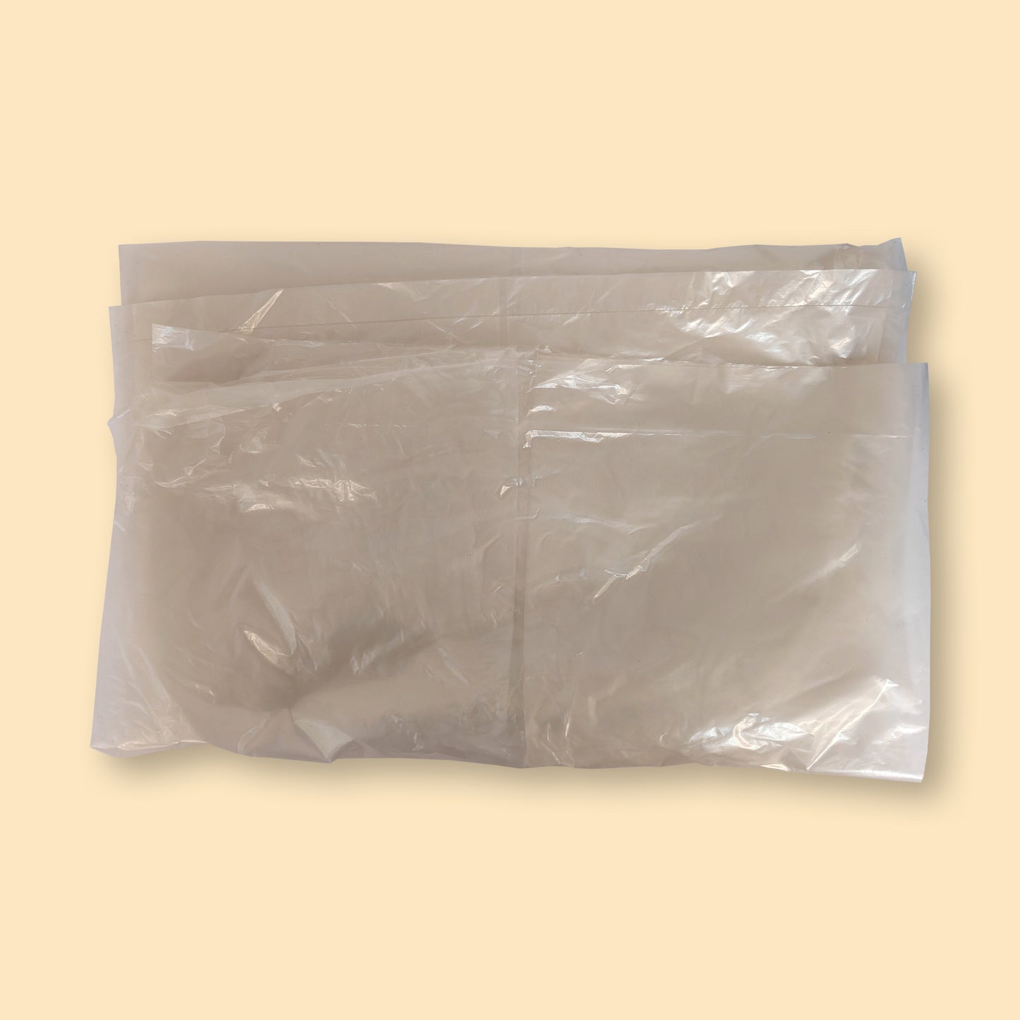 Clear XL garbage bags stacked in a pack of 100, showing transparent plastic material against beige background