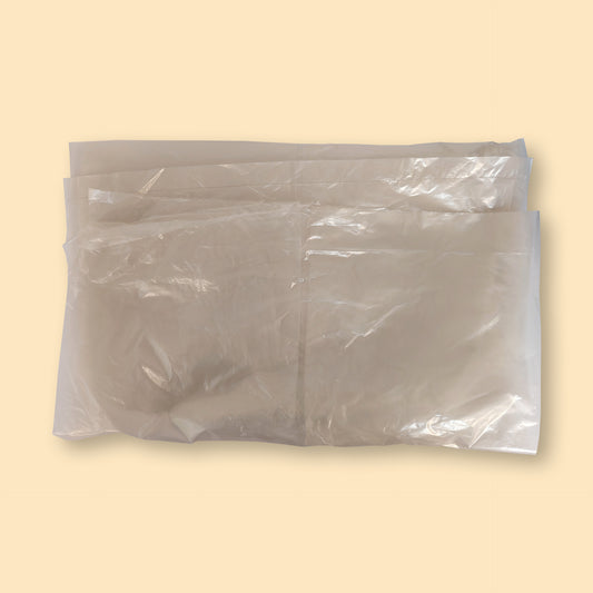 Clear XL garbage bags stacked in a pack of 100, showing transparent plastic material against beige background