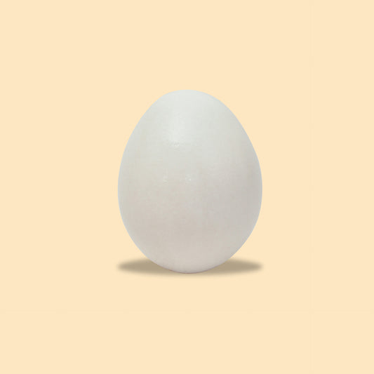 Fresh white extra large egg on peach background with soft shadow, perfect oval shape and smooth shell