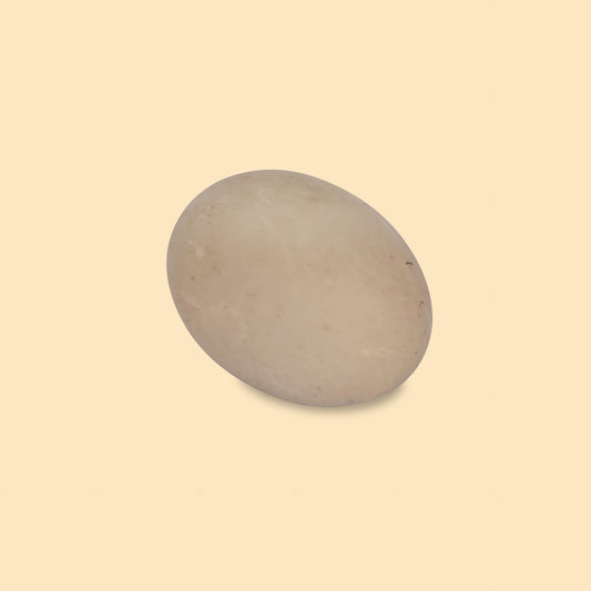 Single preserved salted duck egg with pale gray shell on beige background